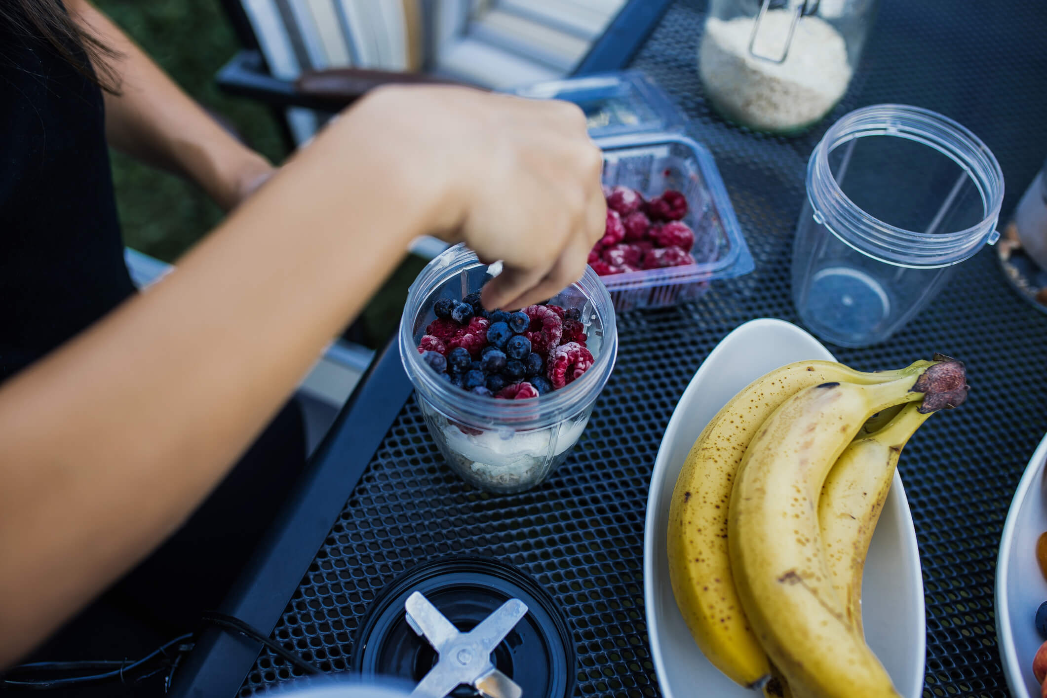 Woman makes a healthy breakfast smoothie in a blender with bananas.