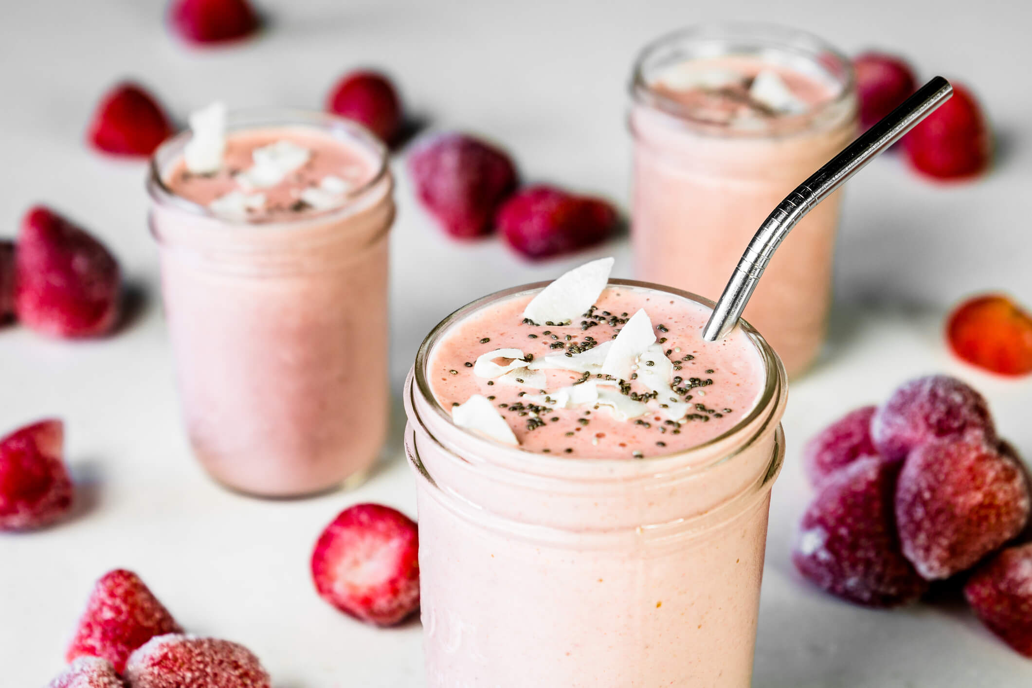 Three healthy strawberry smoothies with coconut flakes