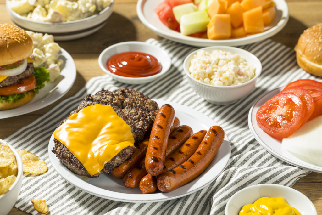 summer cookout menu with hamburgers, hot dogs, fruits, potato salad