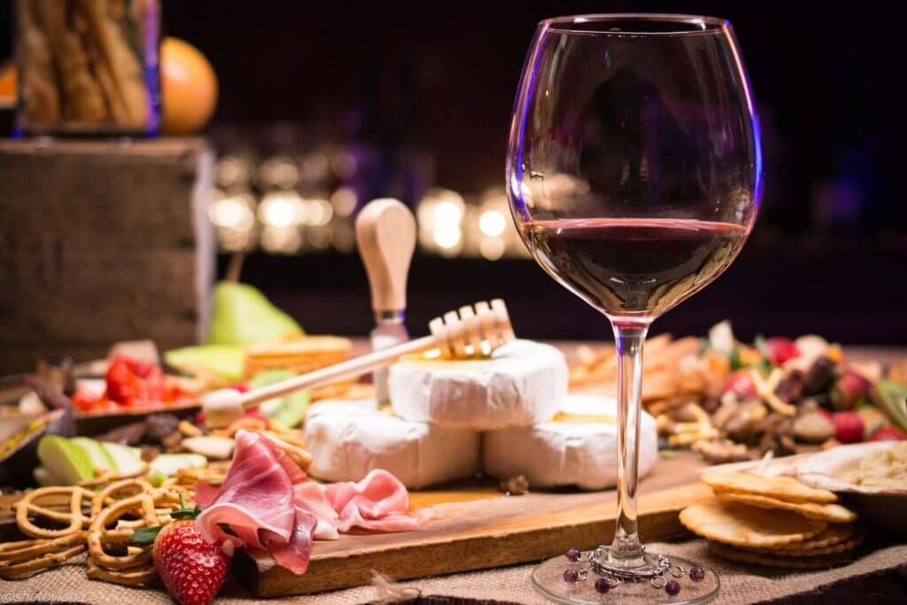 cheese board displayed on table with glass of wine placed next to it