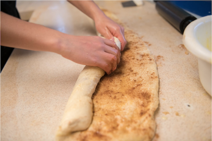 Amish baker rolling cinnamon fresh-made rolls