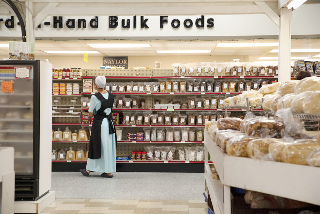 Amish shopkeeper overseeing the shelves at bulk foods stand