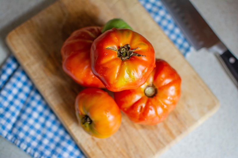 Stack of Beefsteak Tomatoes on a cutting board. 