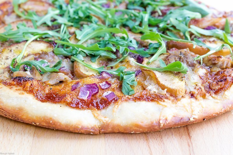 close-up of peach BBQ pizza on wooden countertop