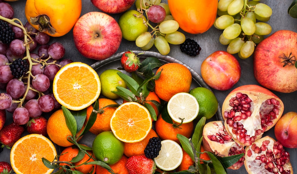 A large assortment of fruits on a gray background.
