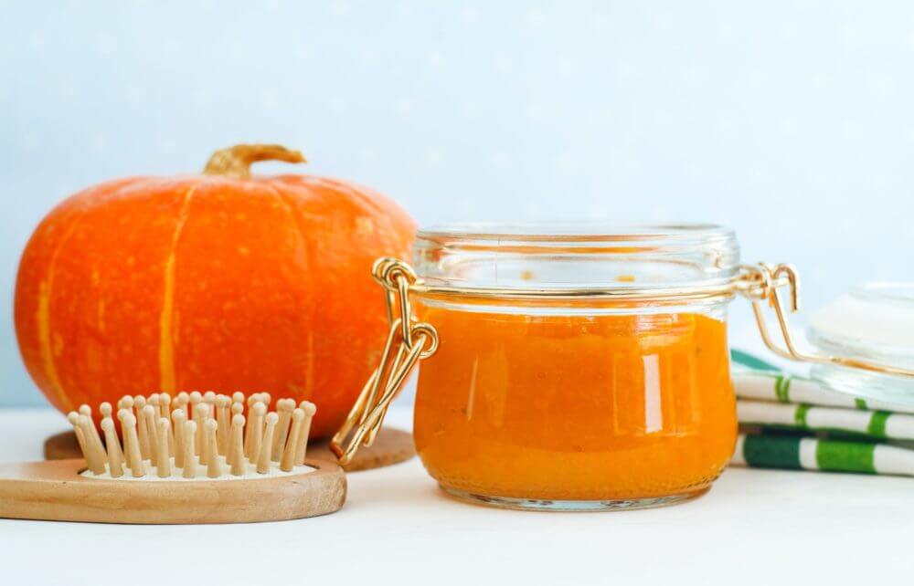 Container of pumpkin next to a pumpkin and a brush. 