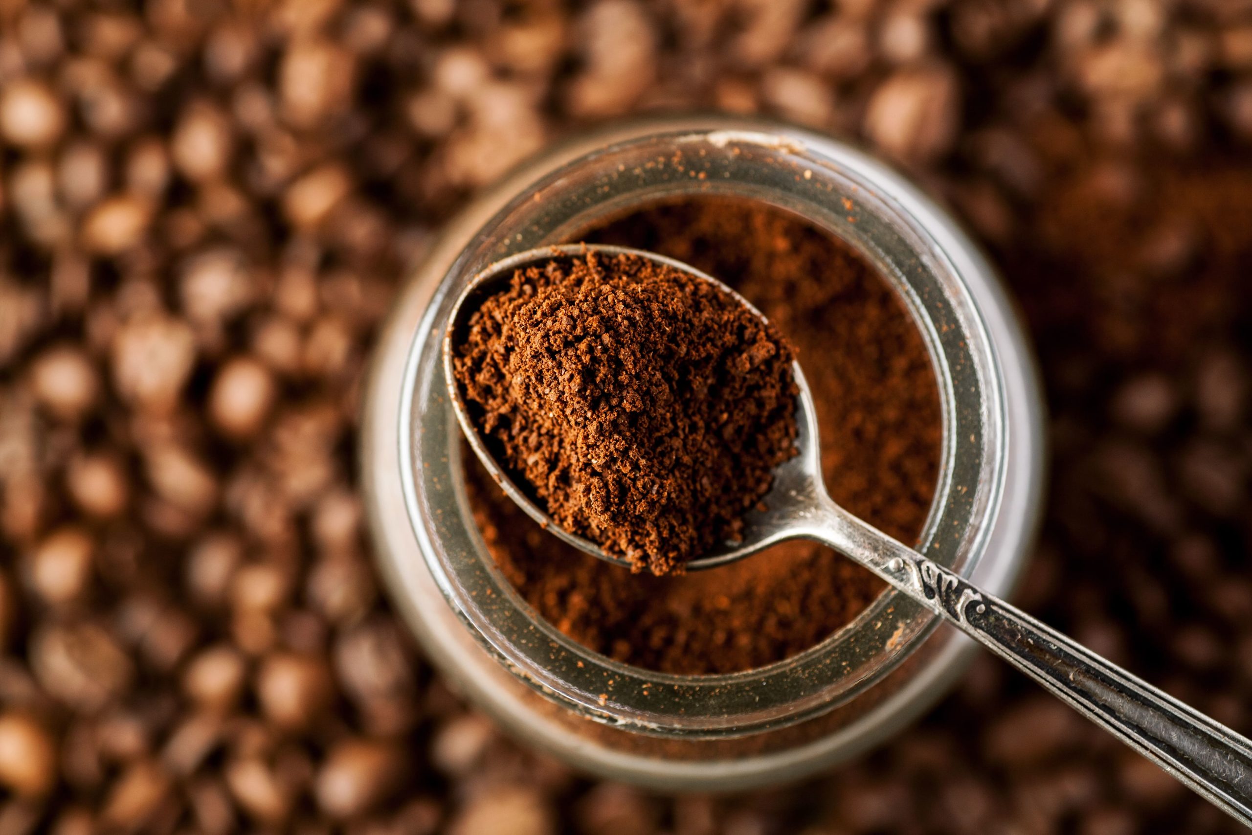 Coffee roasts explained for beginners starts with someone holding a spoon of ground coffee.
