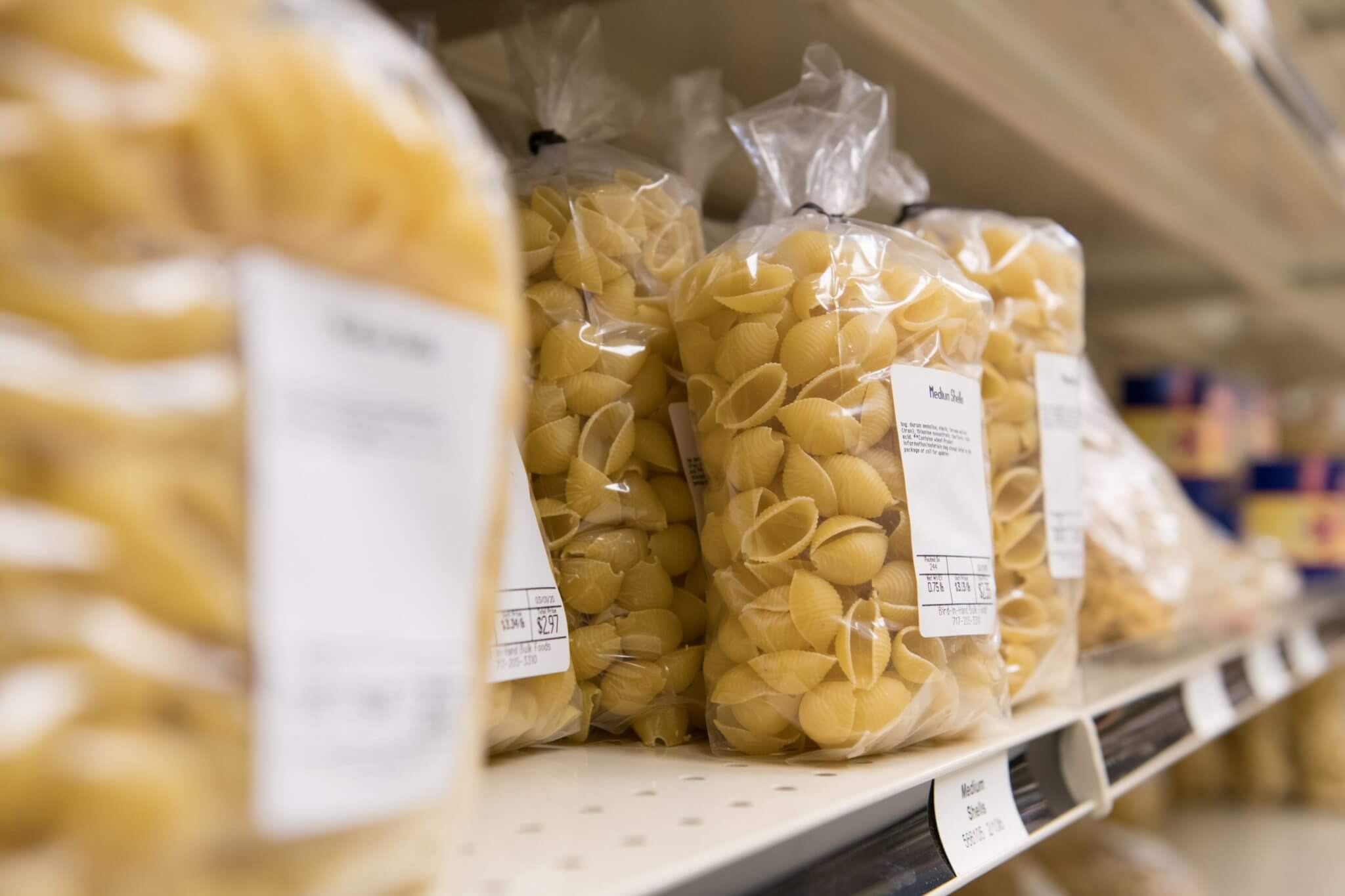 The Markets shelves are lined with a variety of freshly made, bulk pasta for sale in large bags.