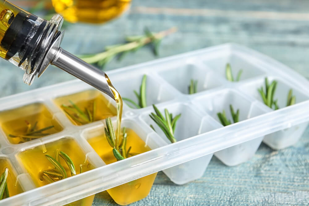 Herbs are lined in an ice cube tray and oil is poured over top.