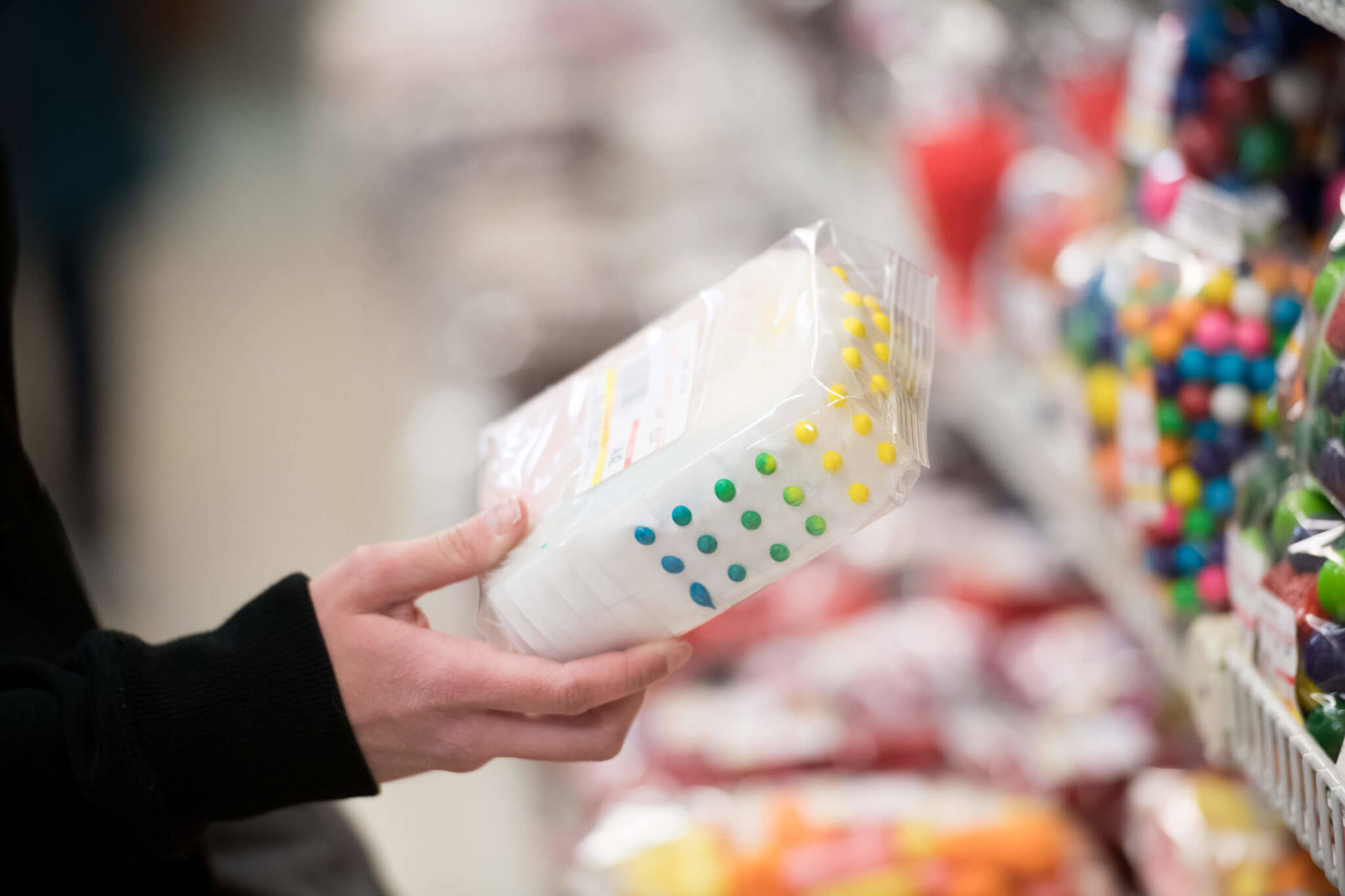 A shopper holds a package of colorful candy dots in a candy store.