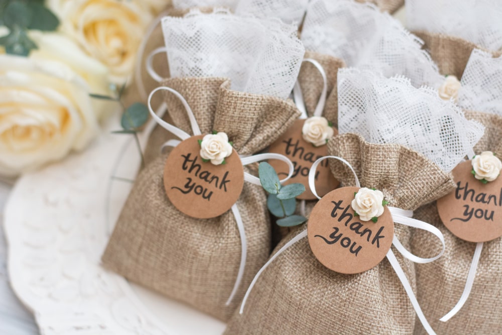 Wedding favor bags resembling small burlap sacks with “thank you” tags tied around them.