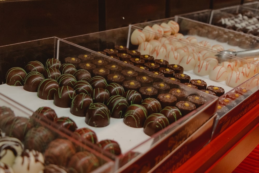 Small chocolate truffles in display cases of a candy shop.