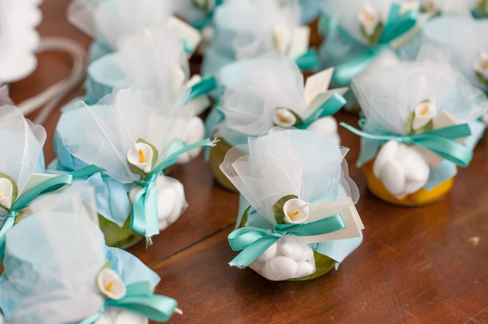 Small lace wedding favor bags tied with light blue ribbon and a small white flower.