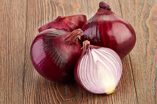 two whole red onions with a halved red onion