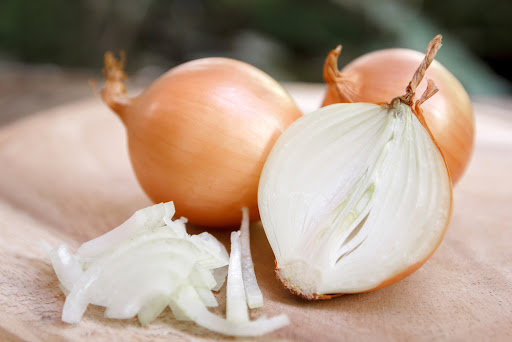 two whole yellow onions with a halved yellow onion