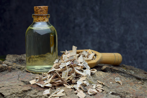 a pile of birch bark scraps sitting next to a small jar of birch oil