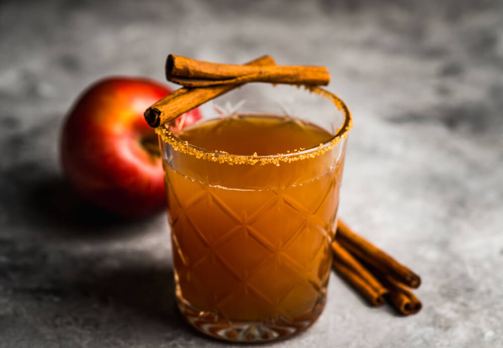 an old fashioned cocktail in a glass with a cinnamon coated rim. 