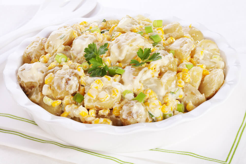 potato salad with sweet corn, green onions, and a parsley garnish