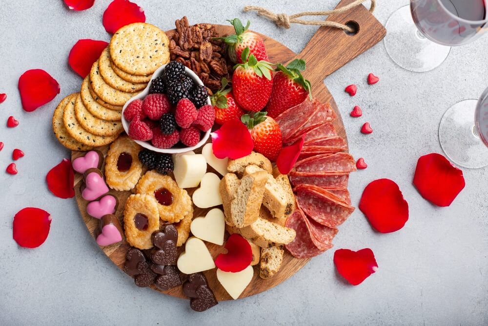 valentine's themed charcuterie board with heart shaped chocolates and cheeses