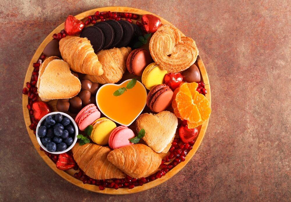 a mother's day charcuterie board with fruit, croissants, macaroons, and chocolate