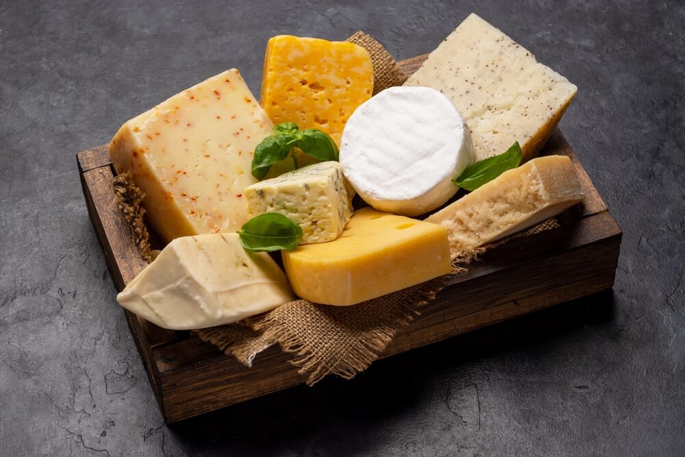 an assortment of blocks of cheeses on a serving platter