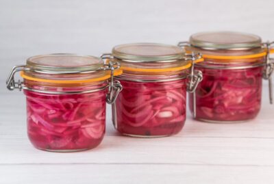 three jars of quick pickled red onions sitting in a row