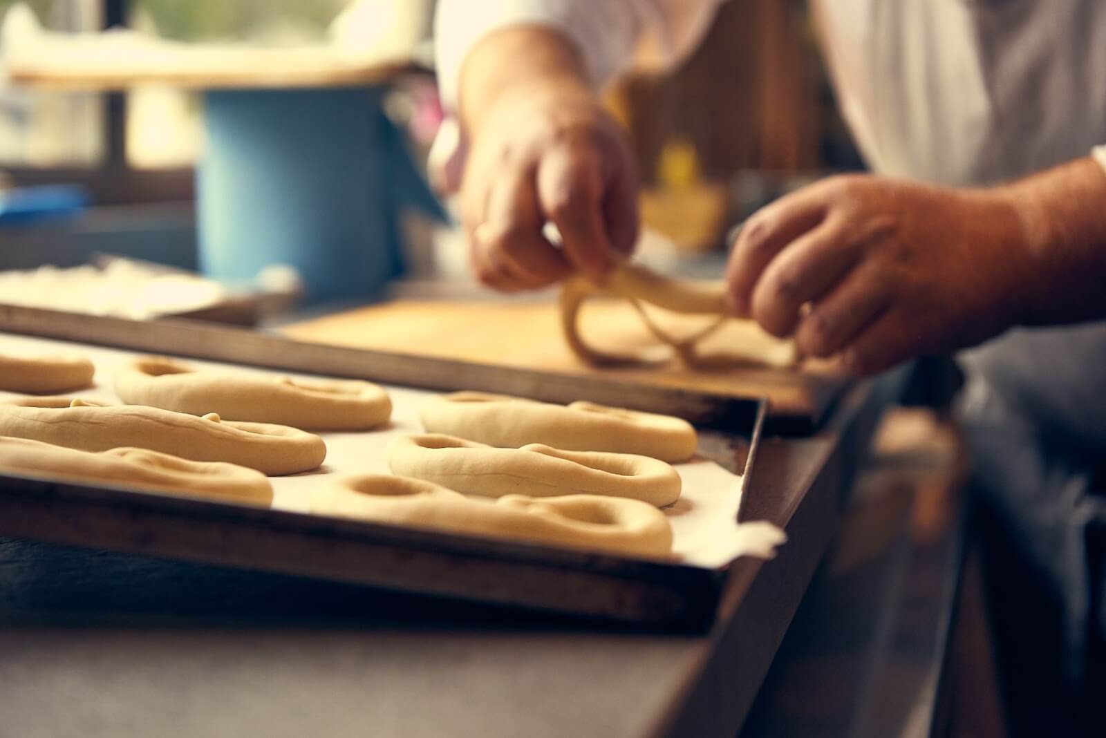 a close up of a person shaping soft pretzels to bake in the oven