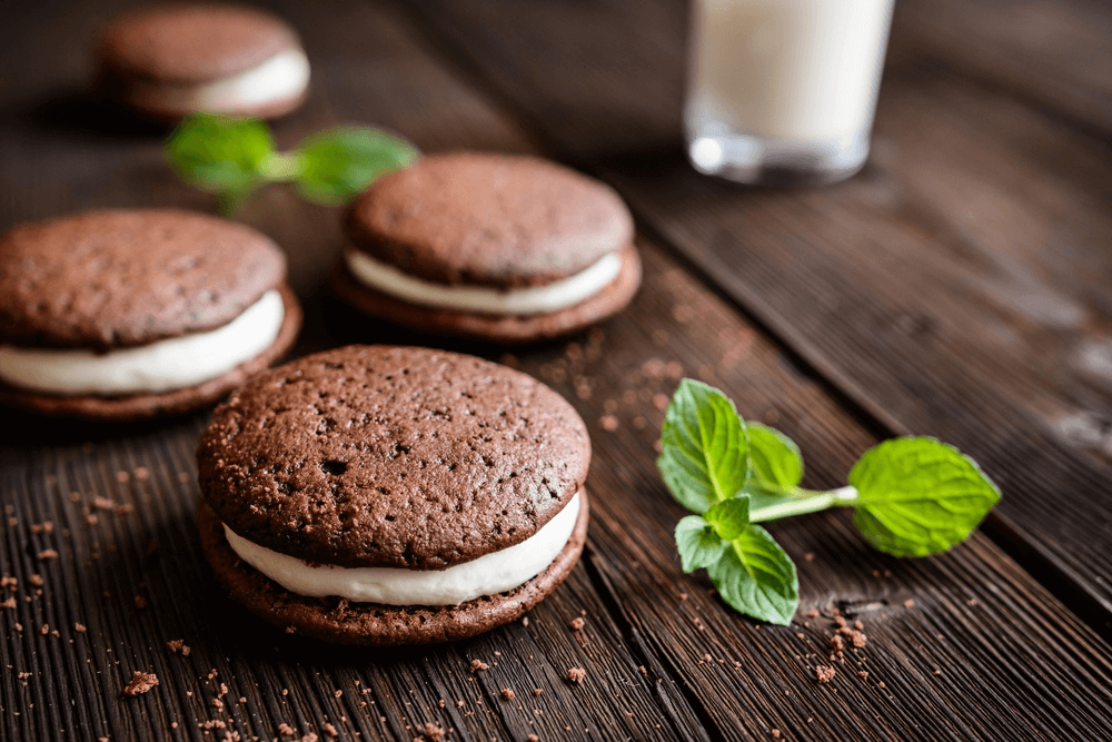 Amish whoopie pies on a wooden table with a glass of milk