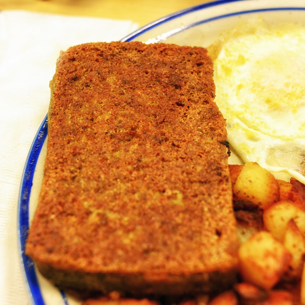 philly-style scrapple served on a plate with eggs and breakfast potatoes