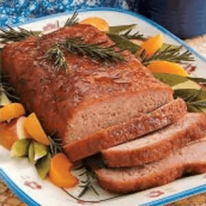 A close-up image of a traditional Amish ham loaf on a plate of vegetables.
