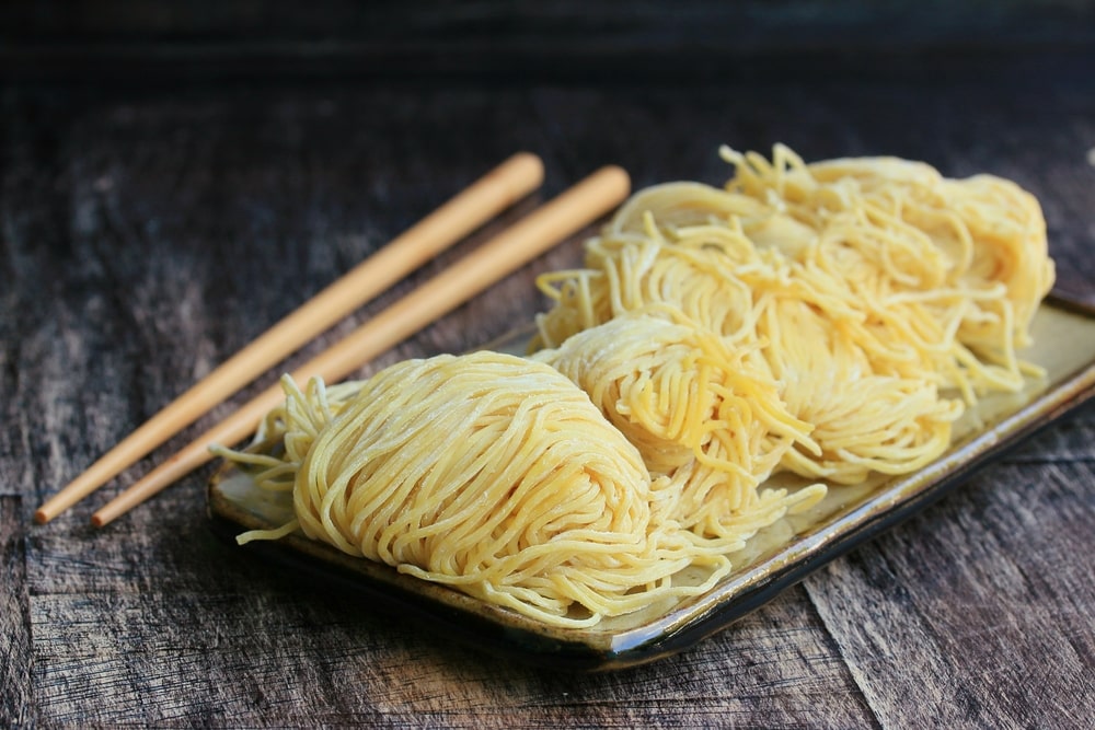 Egg noodles on a rectangular plate with chopsticks.