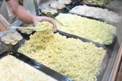 close up on a merchant dishing out some amish macaroni salad into a bowl