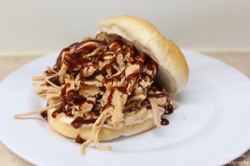 Sandwich from a pulled pork slow cooker recipe on a white dinnerware plate