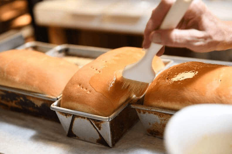 Baker spreading butter with a basting brush for an Amish Dessert Recipe